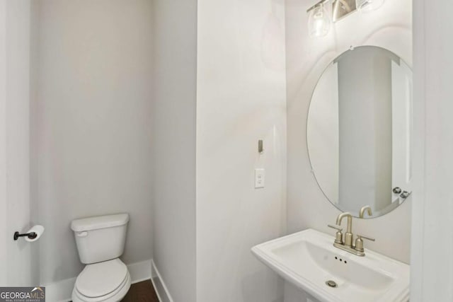 bathroom with a sink, toilet, and baseboards