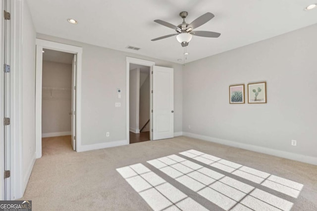 unfurnished bedroom featuring recessed lighting, light colored carpet, a ceiling fan, baseboards, and a spacious closet