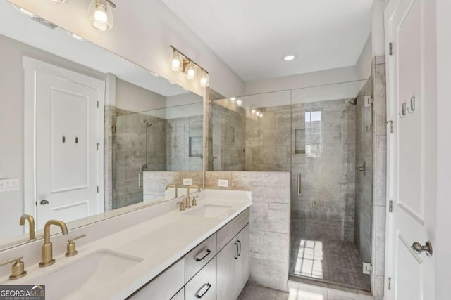 bathroom with double vanity, a shower stall, visible vents, and a sink