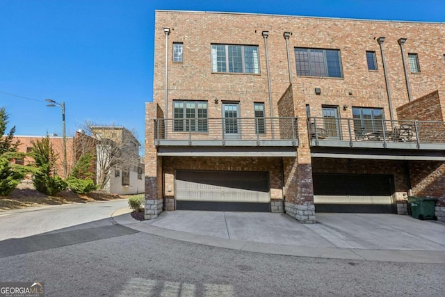 view of front of property featuring an attached garage, concrete driveway, and brick siding