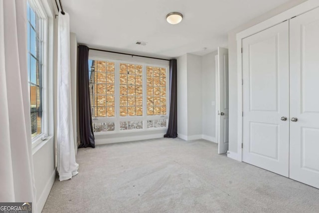 empty room with visible vents, carpet, a wealth of natural light, and baseboards