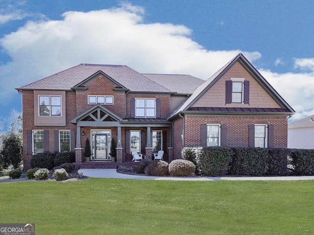 craftsman-style home with a front lawn, a standing seam roof, a shingled roof, and brick siding