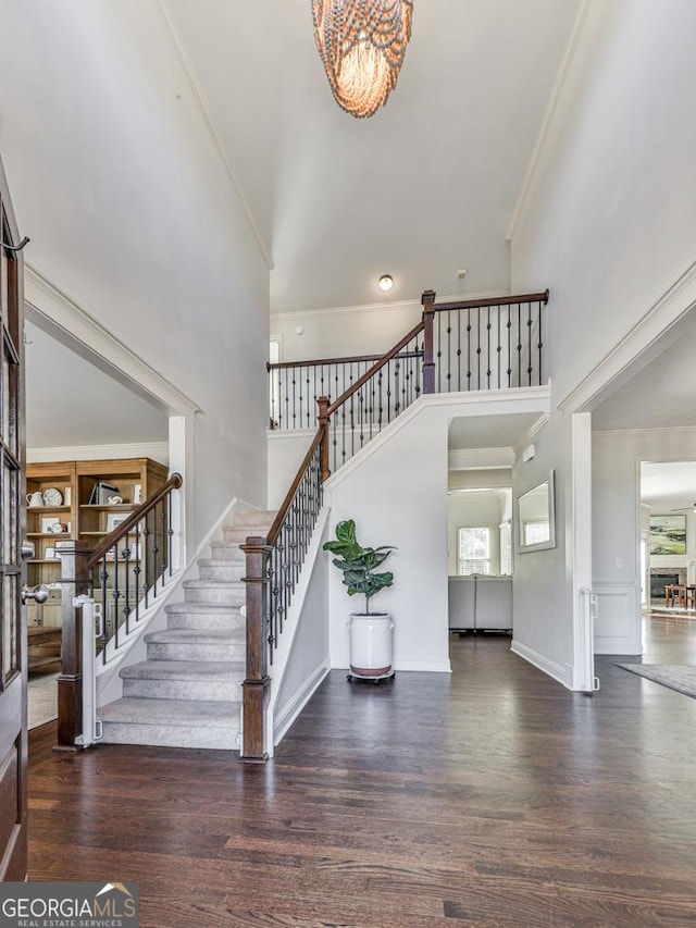 staircase featuring a high ceiling, ornamental molding, and wood finished floors