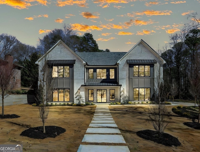 rear view of property featuring metal roof, roof with shingles, and a standing seam roof