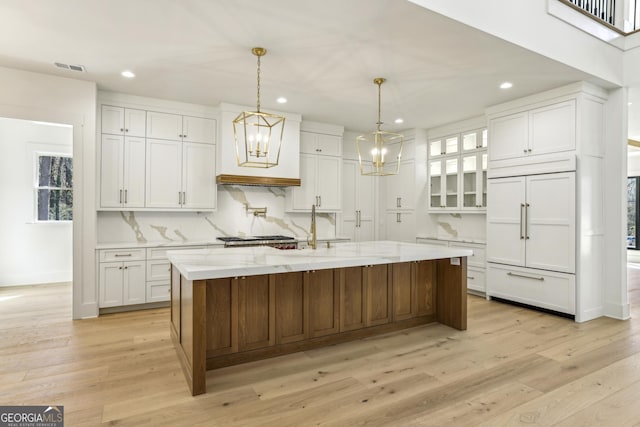 kitchen with built in fridge, light wood-type flooring, white cabinets, and backsplash