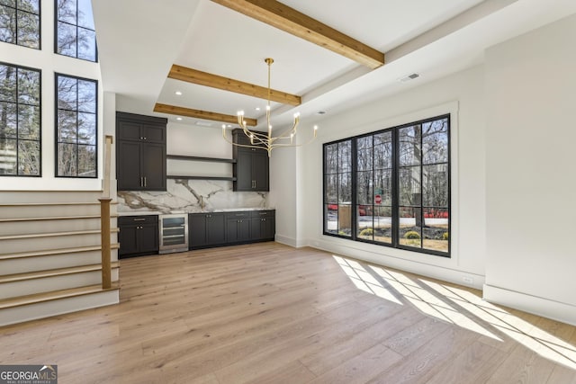 interior space featuring wine cooler, beam ceiling, light wood-style flooring, backsplash, and a chandelier