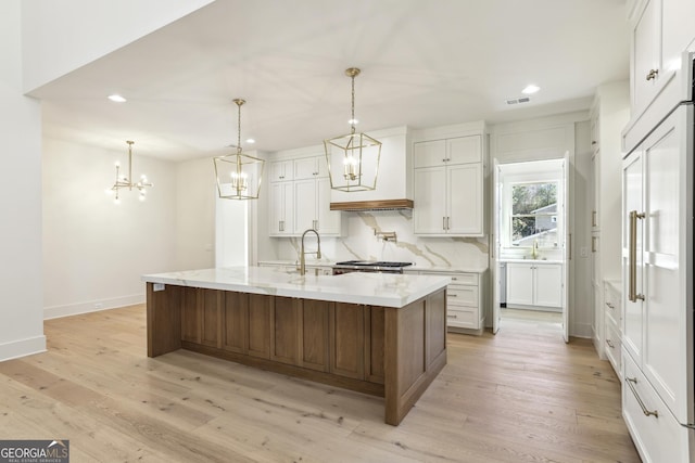 kitchen with light wood-style floors, a sink, visible vents, and decorative backsplash