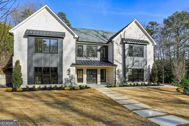 view of front of property with metal roof, brick siding, a standing seam roof, and a front yard