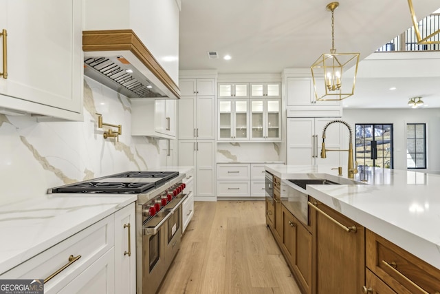 kitchen with range with two ovens, brown cabinetry, a sink, and white cabinetry