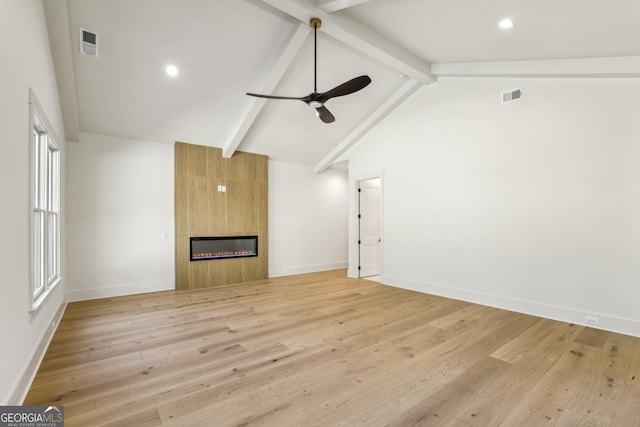 unfurnished living room with a large fireplace, visible vents, and beam ceiling