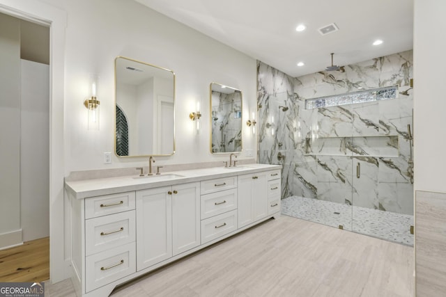 full bathroom with recessed lighting, a sink, a marble finish shower, and double vanity