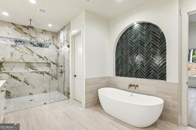 full bathroom featuring a marble finish shower, visible vents, a freestanding bath, tile walls, and recessed lighting