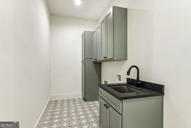 washroom featuring hookup for a washing machine, a sink, baseboards, cabinet space, and light floors