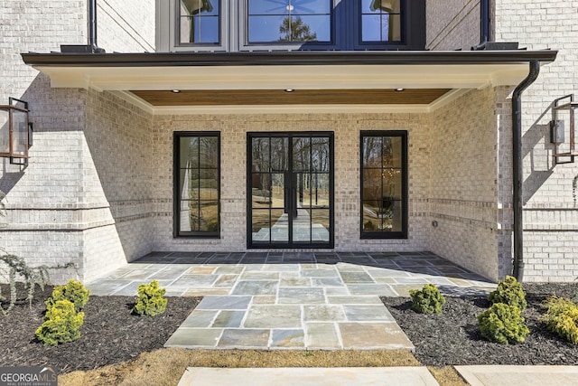 entrance to property featuring french doors, brick siding, and a patio