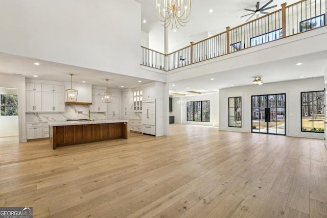 372 Karen Dr, Alpharetta, GA 30009 - unfurnished living room with light wood-type flooring, a high ceiling, ceiling fan, a chandelier, and recessed lighting