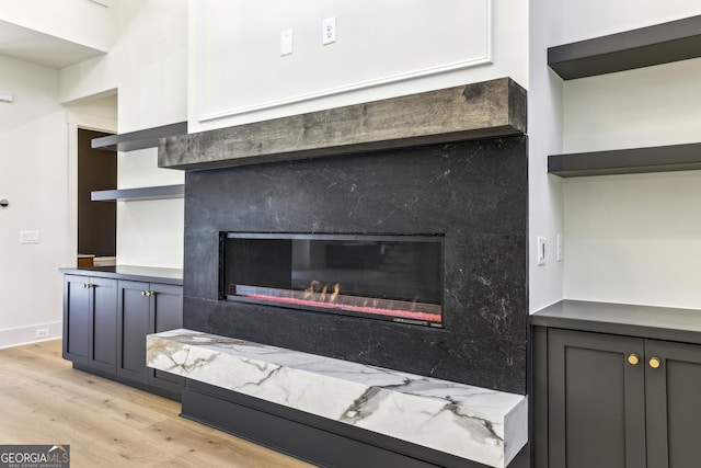 interior details featuring wood finished floors and a glass covered fireplace