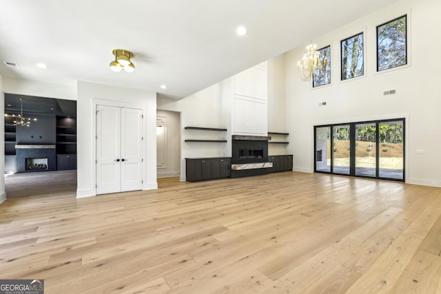 unfurnished living room with recessed lighting, a fireplace, visible vents, baseboards, and light wood finished floors