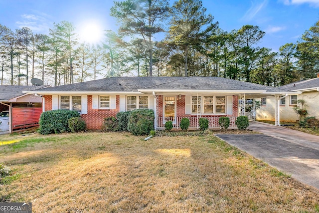 ranch-style home with roof with shingles, brick siding, a front yard, an attached carport, and driveway