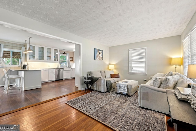 living area with a textured ceiling, plenty of natural light, and dark wood finished floors