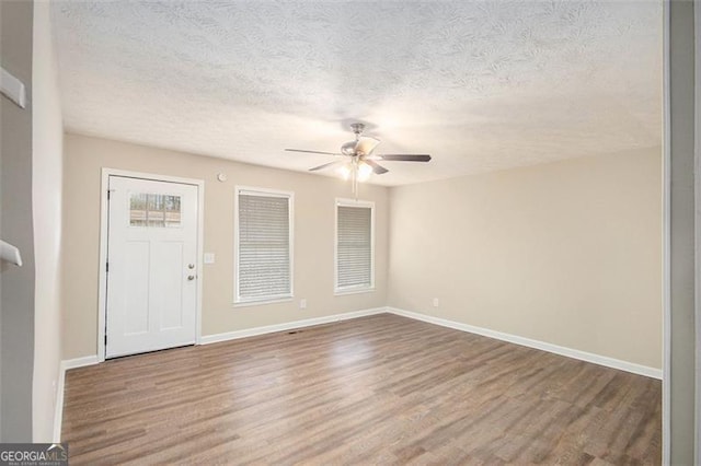 entrance foyer featuring ceiling fan, a textured ceiling, baseboards, and wood finished floors