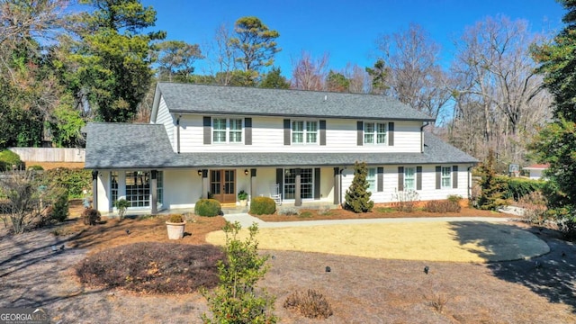 view of front of property featuring covered porch, roof with shingles, and fence