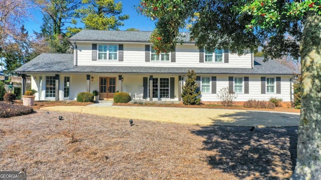 view of front of property with roof with shingles, a porch, and french doors