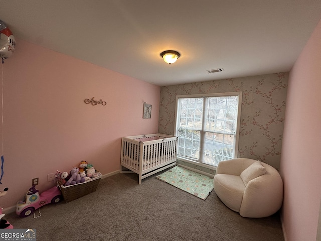 bedroom with visible vents, baseboards, a nursery area, carpet, and wallpapered walls