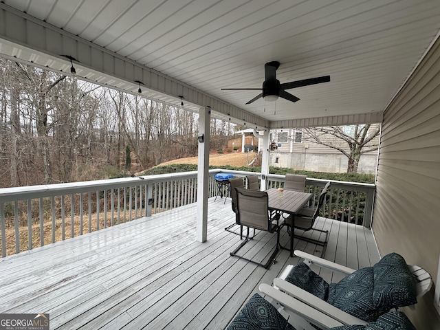 wooden terrace with outdoor dining area and a ceiling fan