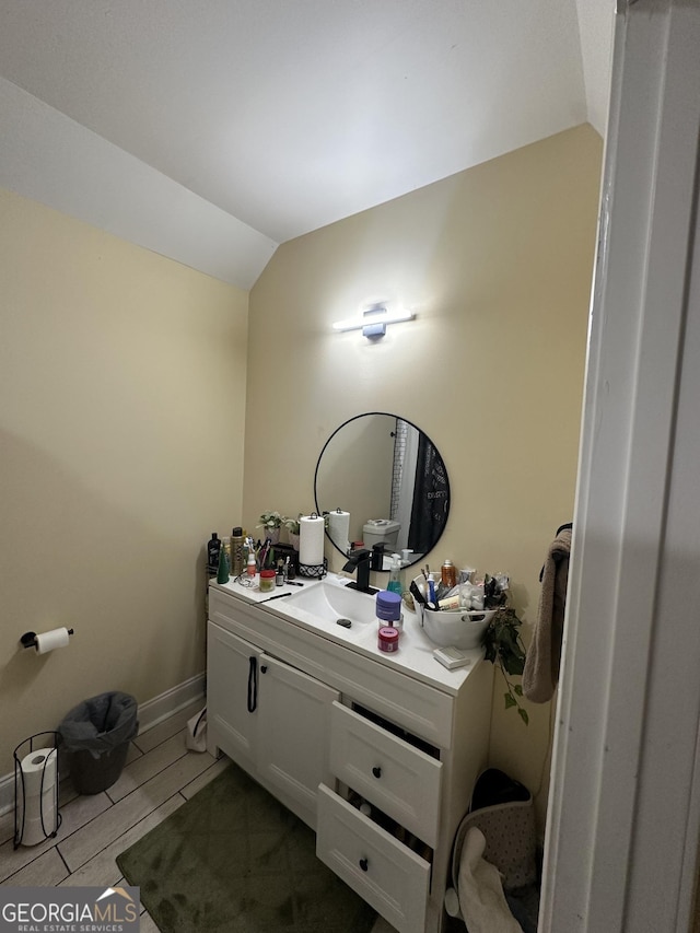 bathroom with lofted ceiling, baseboards, vanity, and wood tiled floor