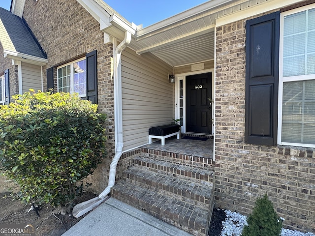 view of exterior entry featuring covered porch and brick siding