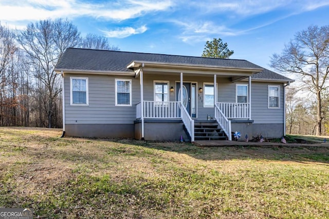 view of front of home featuring covered porch, a shingled roof, and a front yard