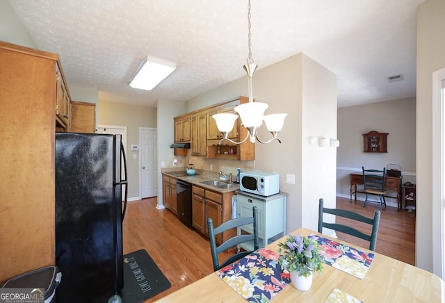 kitchen with visible vents, light wood-style flooring, light countertops, black appliances, and a sink