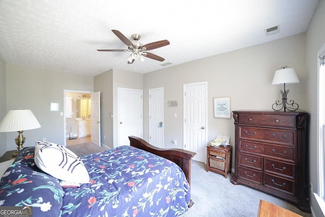 bedroom featuring multiple closets, visible vents, ceiling fan, and light carpet