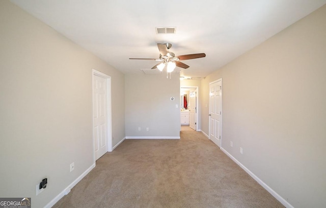 carpeted empty room featuring a ceiling fan, visible vents, and baseboards