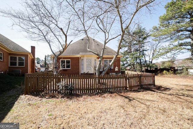 rear view of property with a fenced front yard and brick siding