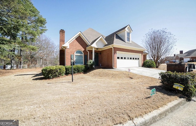 view of front of property with driveway, brick siding, a chimney, and an attached garage