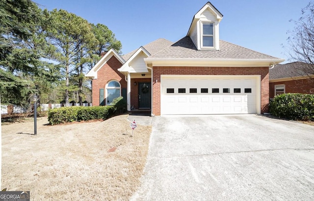 view of front facade with a garage, concrete driveway, brick siding, and roof with shingles