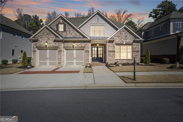 craftsman-style house featuring a standing seam roof, brick siding, and driveway