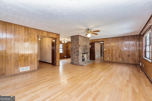 unfurnished living room with light wood-type flooring, a fireplace, visible vents, and a healthy amount of sunlight