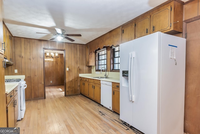 kitchen featuring light wood finished floors, light countertops, brown cabinetry, a sink, and white appliances