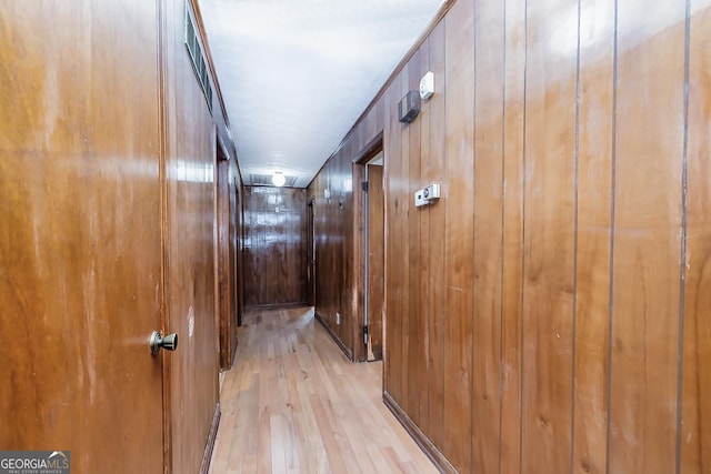 hallway featuring light wood finished floors and wood walls