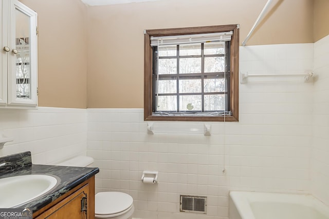 full bath with a wainscoted wall, tile walls, visible vents, toilet, and vanity