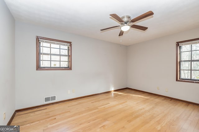 unfurnished room featuring wood finished floors, visible vents, a ceiling fan, and baseboards