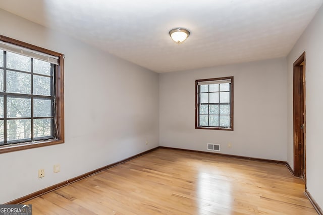 empty room featuring baseboards, visible vents, and light wood finished floors