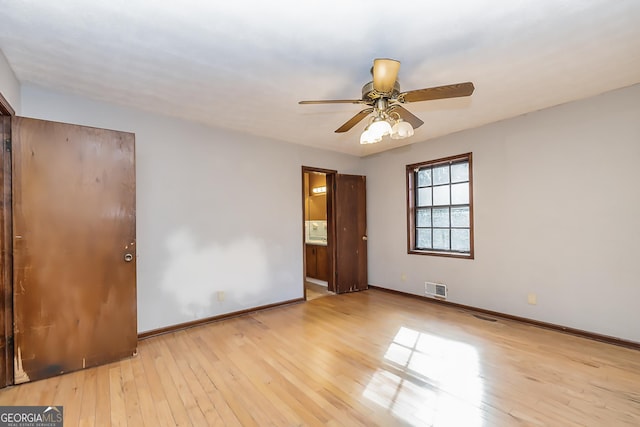 empty room with a ceiling fan, wood-type flooring, visible vents, and baseboards