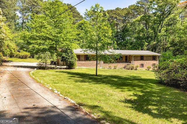 view of front of home with driveway, a front lawn, brick siding, and a chimney