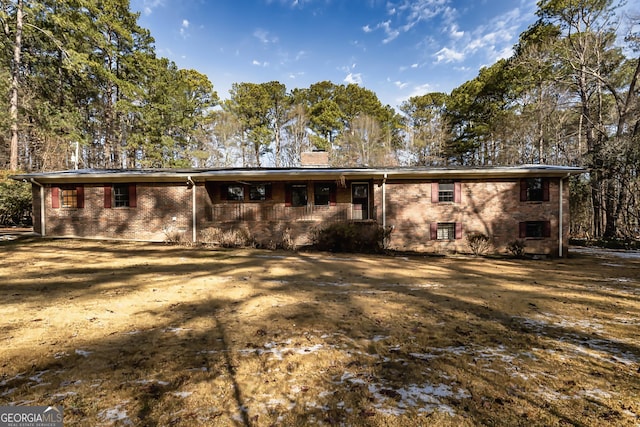 rear view of property featuring brick siding, a chimney, and covered porch
