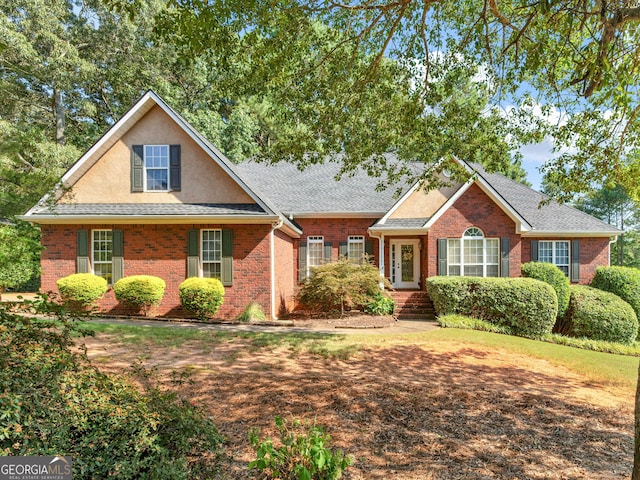 traditional home with a shingled roof, brick siding, and stucco siding