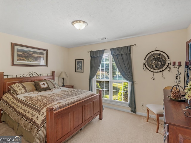 bedroom with visible vents, light carpet, baseboards, and a textured ceiling