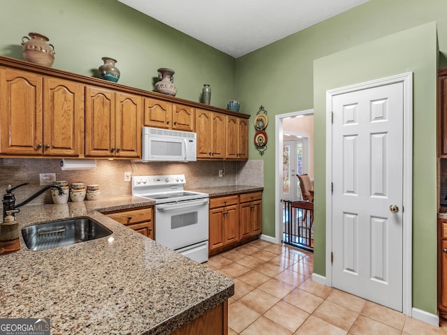 kitchen featuring light tile patterned floors, white appliances, a sink, and tasteful backsplash